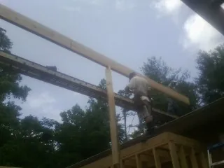 Carpenter setting a ridge beam over a new addition frame — Ice Dam Removal by Roofing Brothers in Milanville