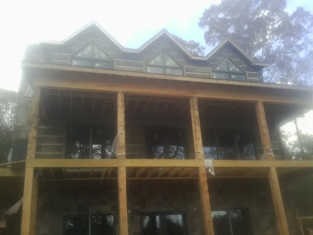 Dormers and porch framing on a large log home under construction — Roof Coating work by our crew in Milanville