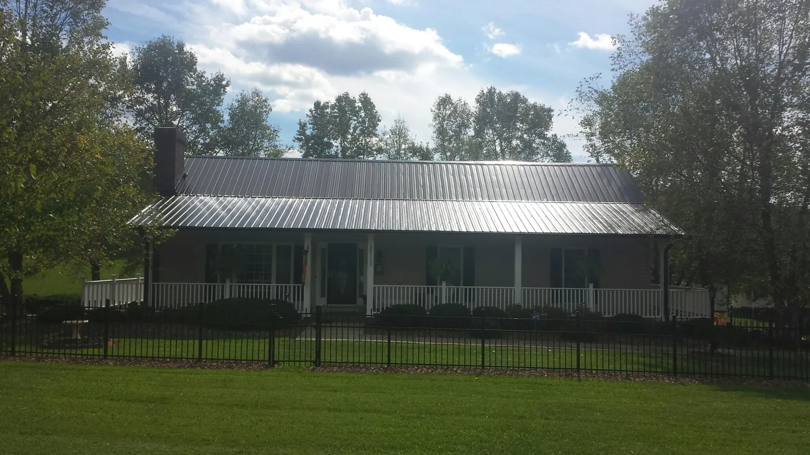 Gray metal roof on a brick ranch with a full width front porch — Gutter Guard Installation work by our crew in Milanville