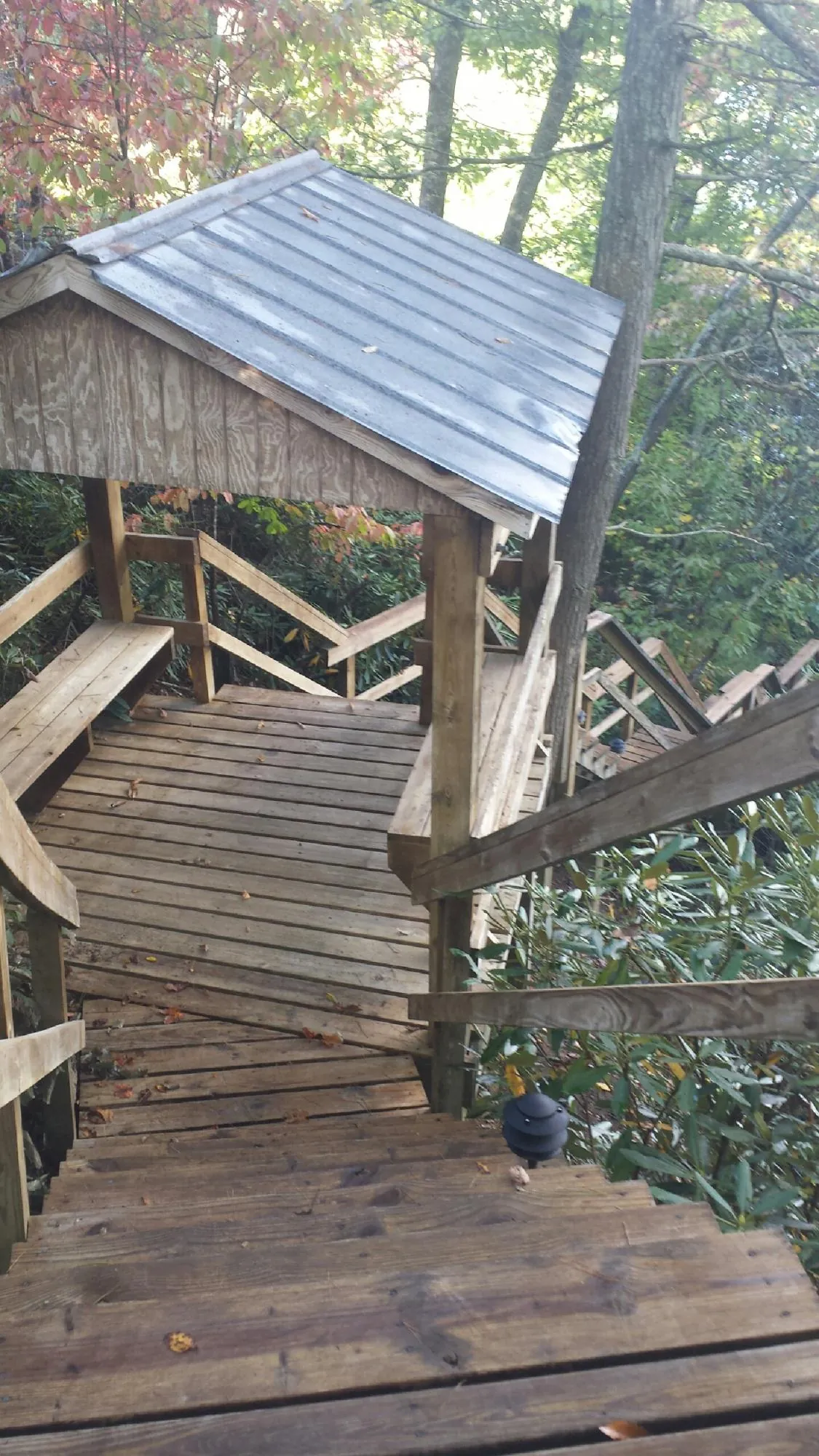 Metal roofed shelter over wooden steps on a wooded walkway — Skylight Repair & Installation work by our crew in Milanville
