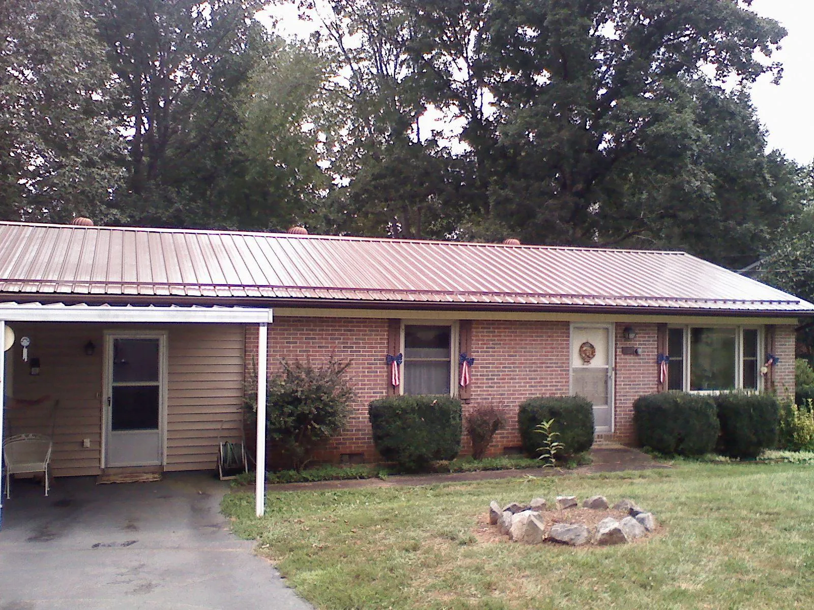 Bronze metal roof and carport on a brick ranch home — Roof Repair work by our crew in Milanville