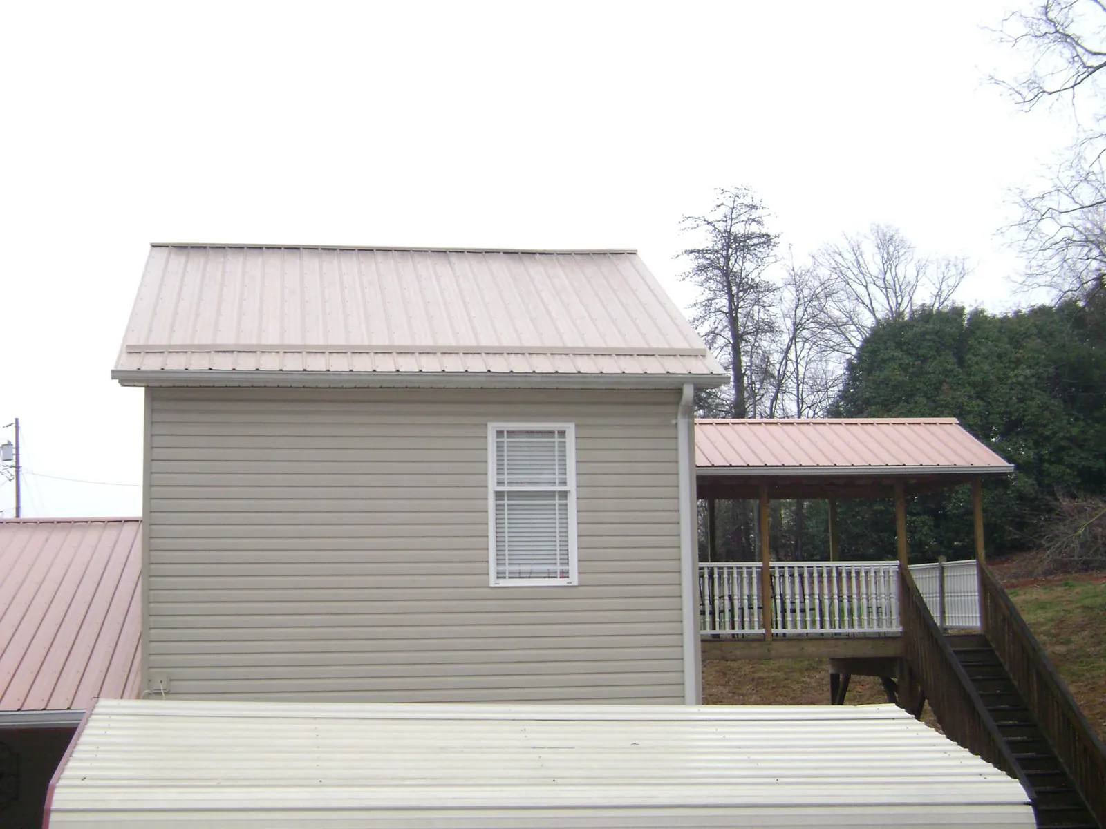 Tan metal roofs on a two story addition and attached porch, from a Roof Replacement job in Milanville