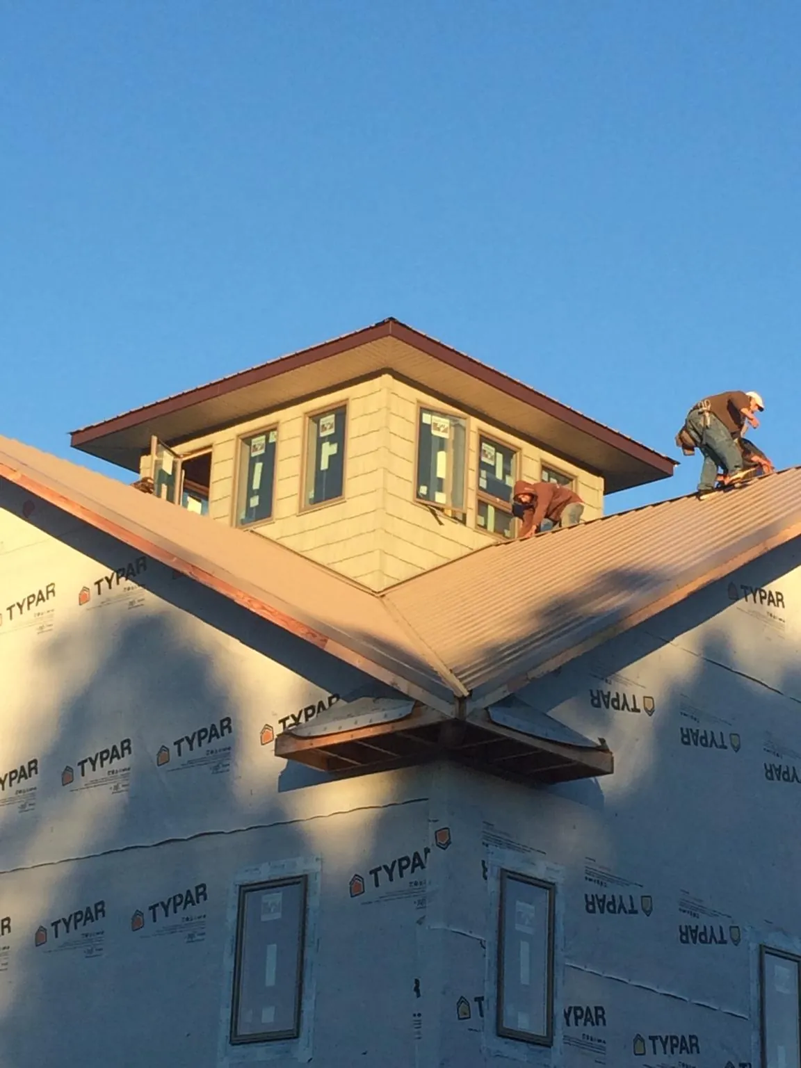 Roofers working around a rooftop cupola on a new metal roof at sunset — Roof Waterproofing in Milanville by Roofing Brothers